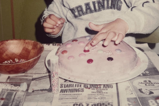 Photo of a child's hand decorating a home made birthday cake 